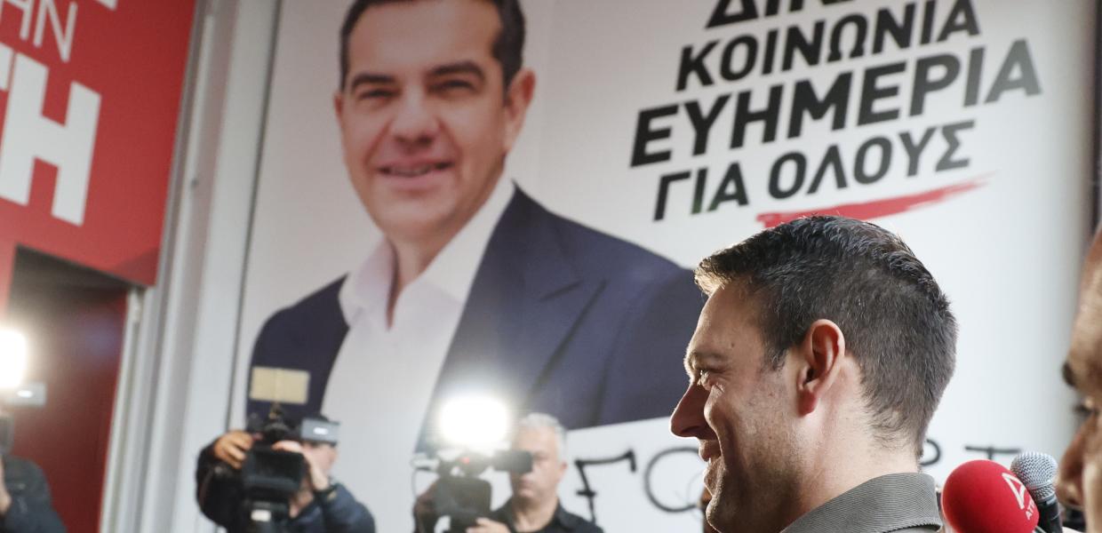 Ο Στέφανος Κασσελάκης και στο βάθος αφίσα του Αλέξη Τσίπρα