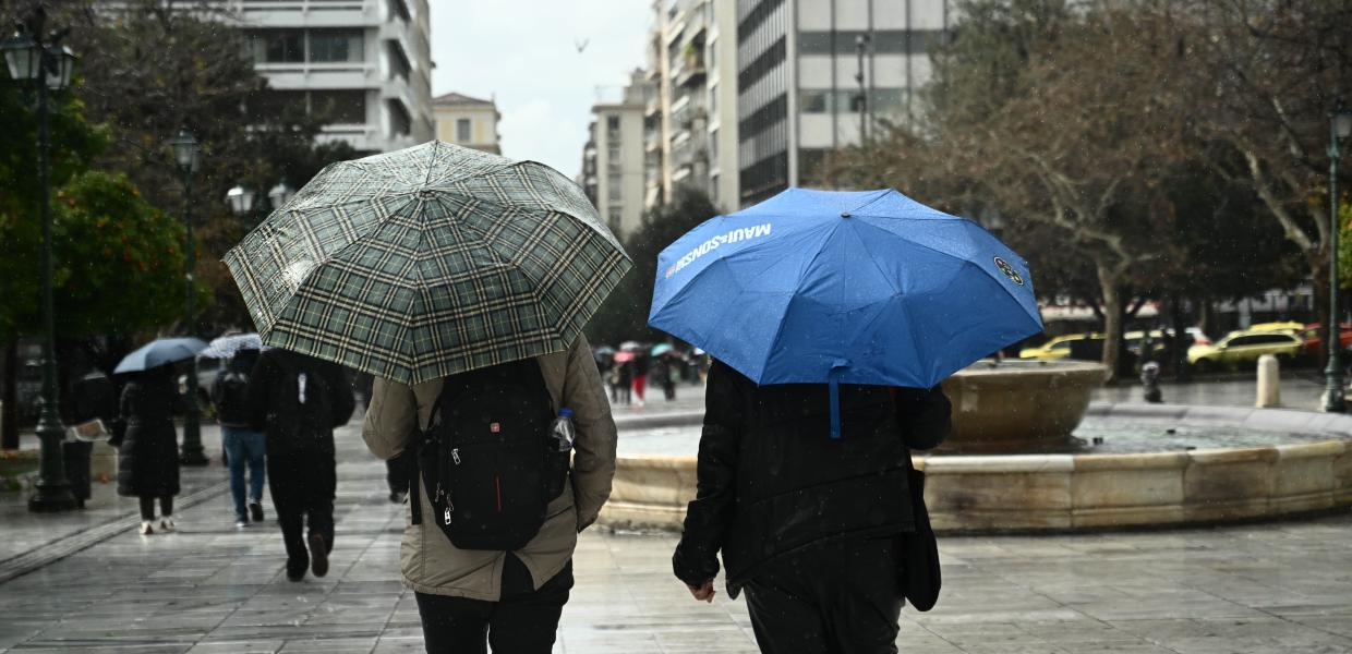 Δύο ανθρωποι με ομπρέλες γυρισμένοι πλάτη περπατούν στην πλατεία Συντάγματος