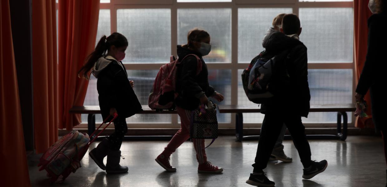 Παιδιά με τσάντες σε διάδρομο σχολείου μπροστά από παράθυρο