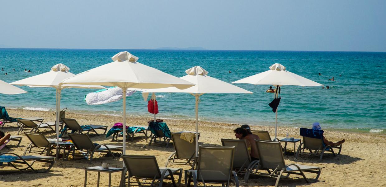Ξαπλώστρες με ομπρέλες μπροστά στην θάλασσα