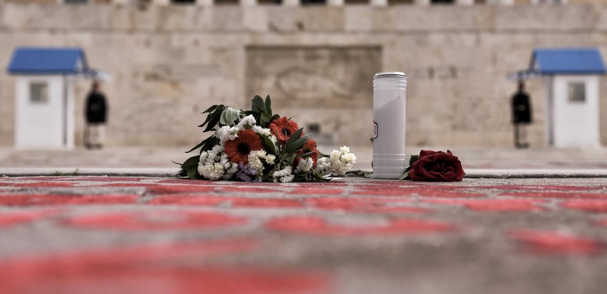 λουλούδια αφημένα μπροστά στο μνημείο του Αγνώστου Στρατιώτη και τα ονόματα των νεκρών στα Τέμπη γραμμένα με κόκκινη μπογιά στην άσφαλτο