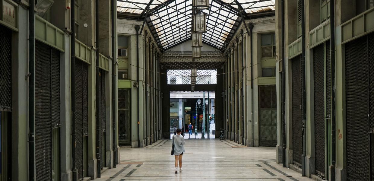 Άνθρωπος περπατά σε στοά στο κέντρο της Αθήνας