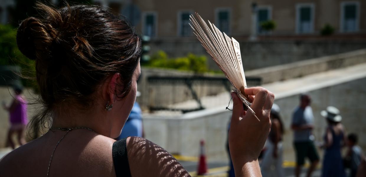 Κοπέλα κάνει σκιά στο πρόσωπό της με βεντάλια στο κέντρο της Αθήνας