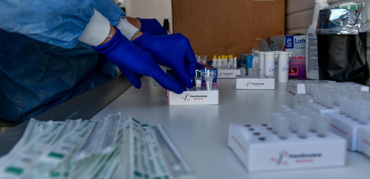 Χέρια γιατρού που φορά ειδικά γάντια και στολή πιάνει τεστ για τον κορωνοιο