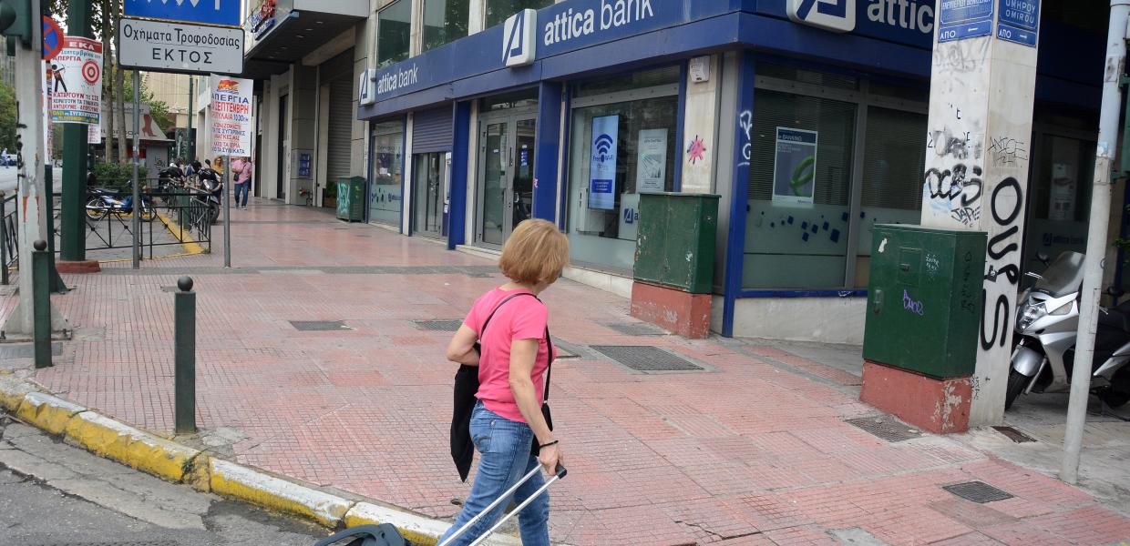 Γυναίκα περπατά έξω από την Attica Bank