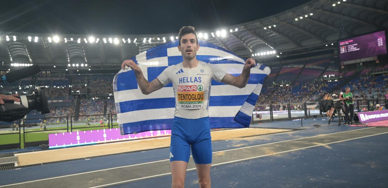 Ο Μίλτος Τεντόγλουμε την ελληνική σημαία στους ώμους του