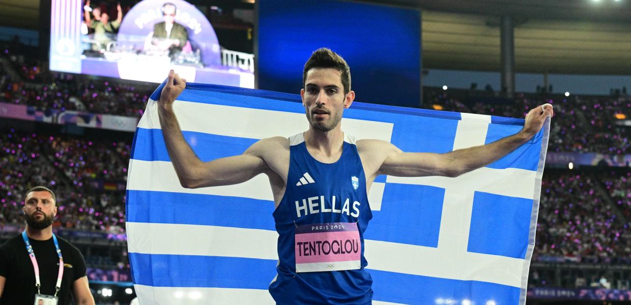 Ο Μίλτος Τεντόγλου τυλιγμένος με την ελληνική σημαία
