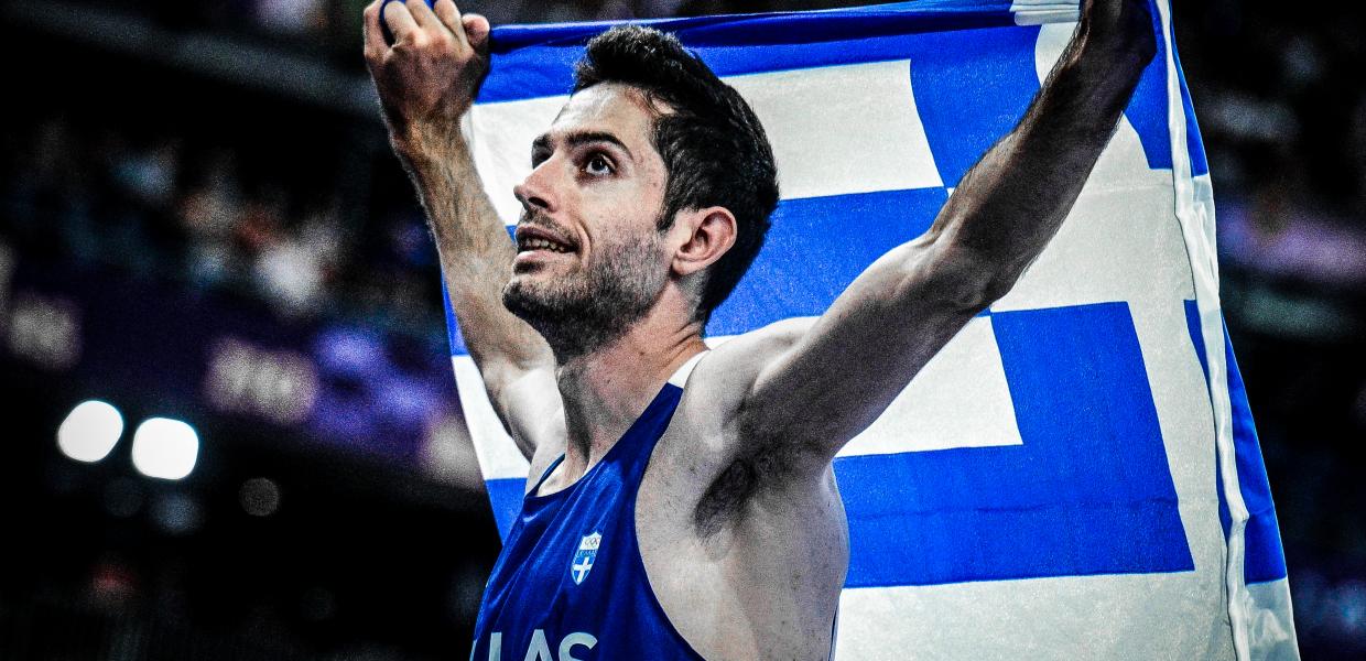Ο Μίλτος Τεντόγλου κρατώντας την ελληνική σημαία