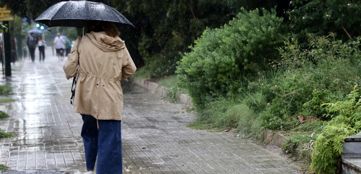 Γυναίκα με ομπρέλα περπατά στη βροχή