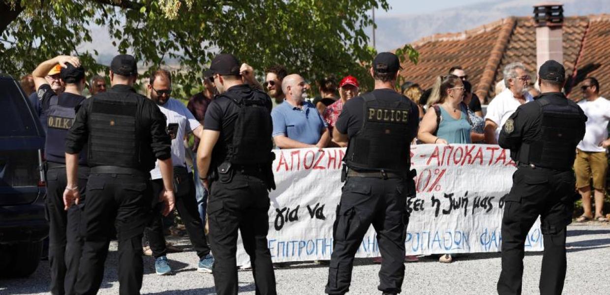 Αστυνομικοί μπροστά σε συγκεντρωμένος με πανό στον Παλαμά για την επίσκεψη Μητσοτάκη