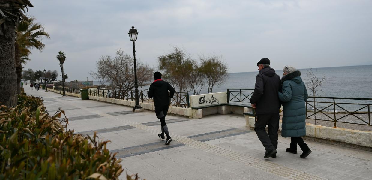 Άνθρωποι με μπουφάν σε παραλιακό πεζόδρόμο