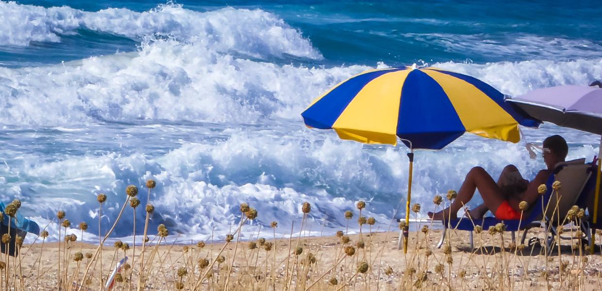 τουρίστας τουρίστες τουρισμός ομπρέλα παραλία κύματα