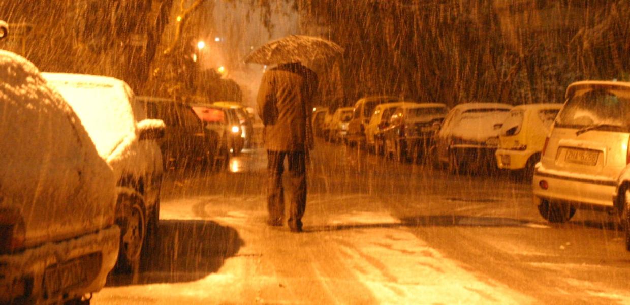 Άνθρωπος με ομπρέλα νύχτα στο δρόμο την ώρα που χιονίζει
