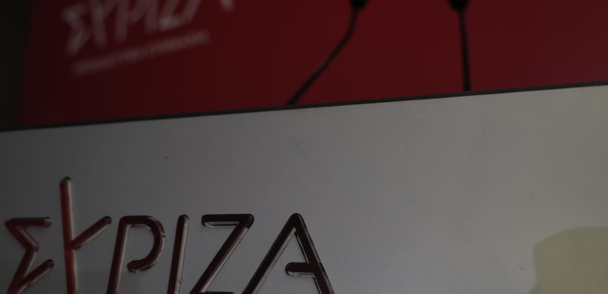 Πόντιουμ με μικρόφωνα και το σήμα του ΣΥΡΙΖΑ-ΠΣ