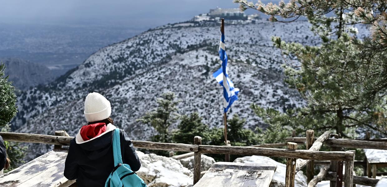 Άνθρωπος κοιτάει την χιονισμένη Πάρνηθα