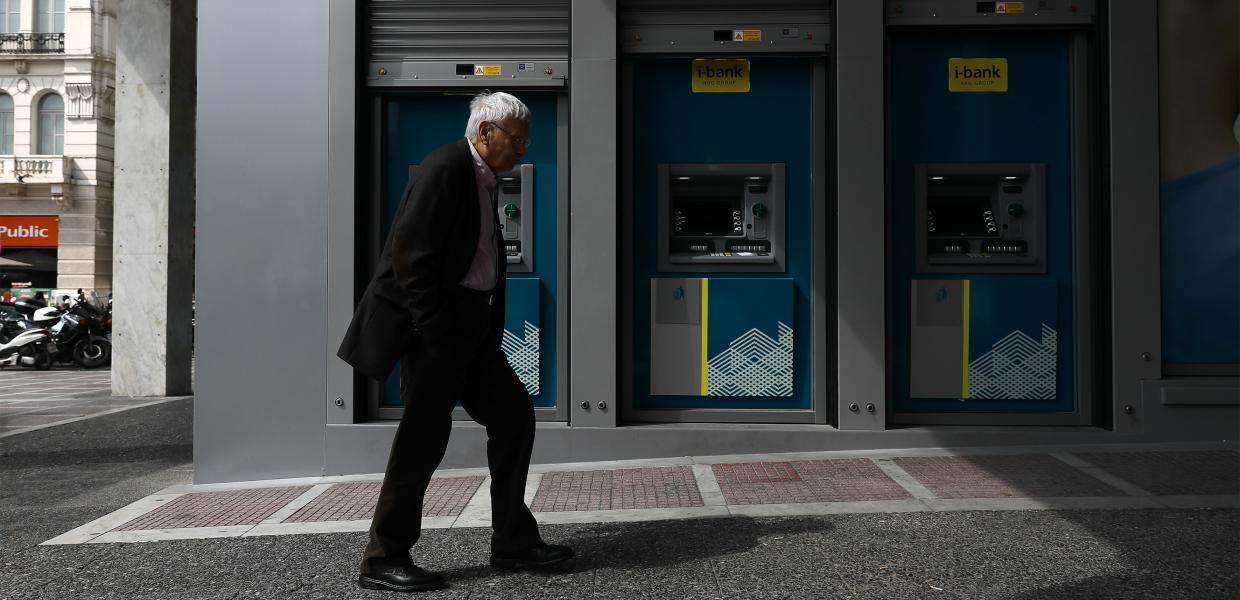 Άνδρας περνά μπροστά από μηχανήματα ΑΤΜ στην πλατεία Συντάγματος