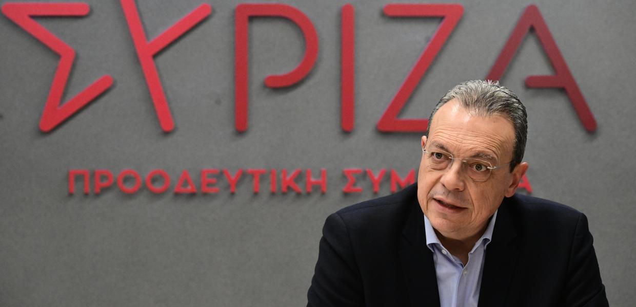 Ο Σωκράτης Φάμελλος καθήμενος μπροστά στο σήμα του ΣΥΡΙΖΑ-ΠΣ
