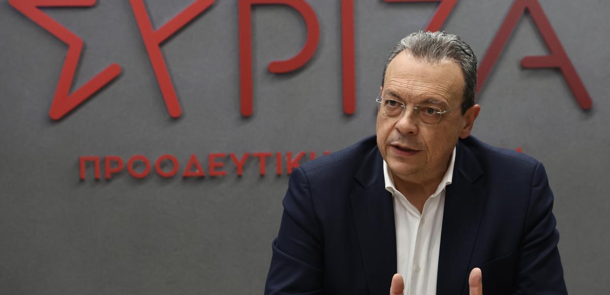 Ο Σωκράτης Φάμελλος καθήμενος μπροστά στο σήμα του ΣΥΡΙΖΑ-ΠΣ