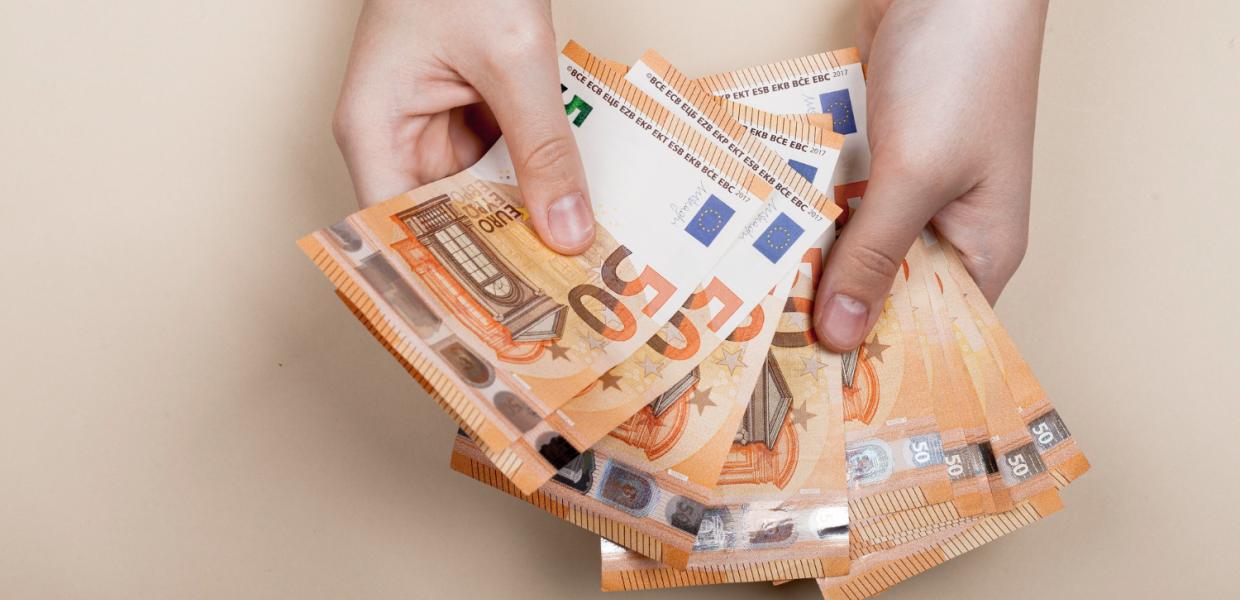 Ζευγάρι χέρια ανοίγουν σα βεντάλια χαρτονομίσματα ευρώ