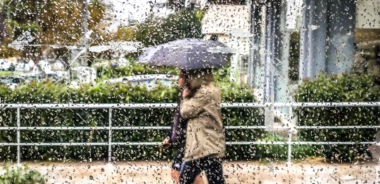 Άτομα με ομπρέλα περπατάνε στη βροχή