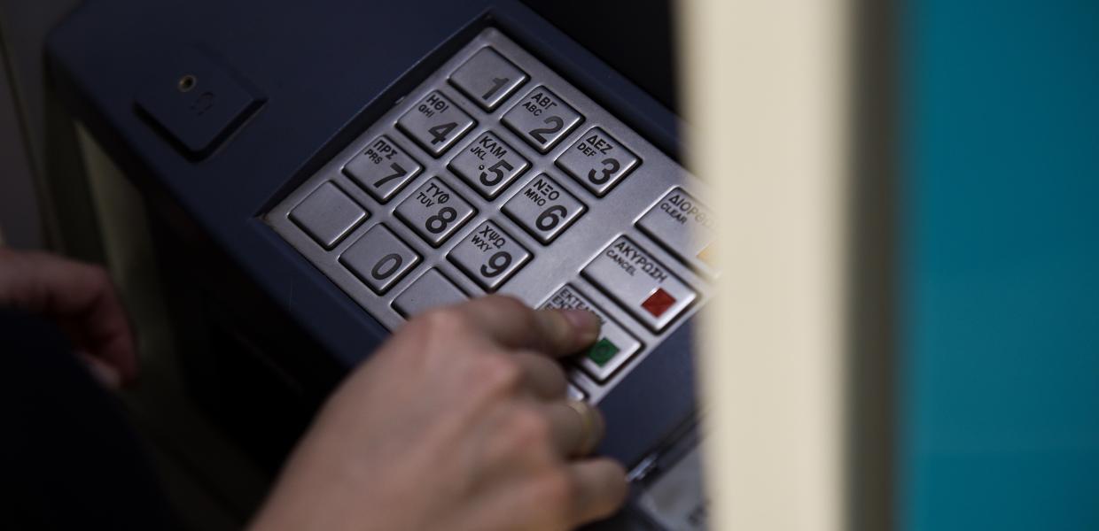 Χέρι πατάει κουμπί σε πληκτρολόγιο μηχανήματος ΑΤΜ