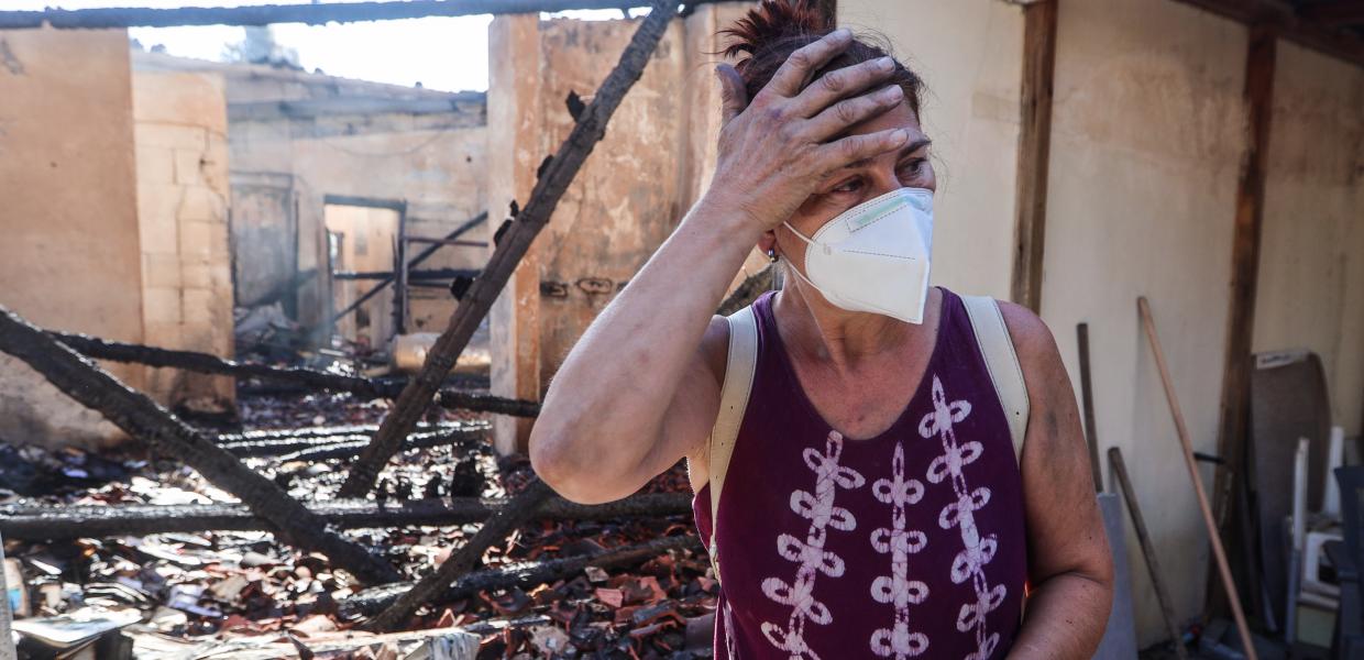 Γυναίκα σε κατεστραμμένη οικία μετά την πυρκαγιά στο Κρυονέρι Αττικής