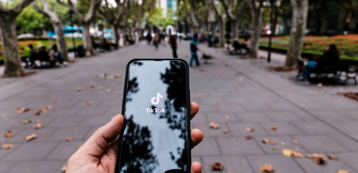 Χέρι κρατάει κινητό με το λογότυπο του TikTok στην οθόνη 