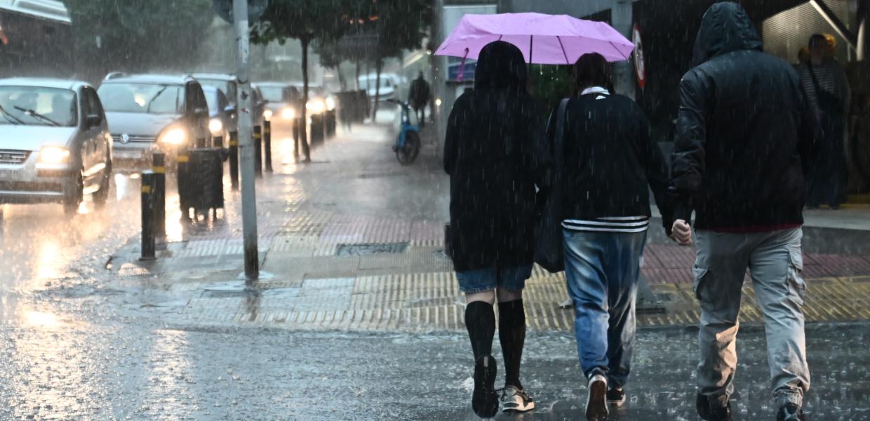 Κόσμος περπατά στην βροχή με μπουφάν και ομπρέλες 