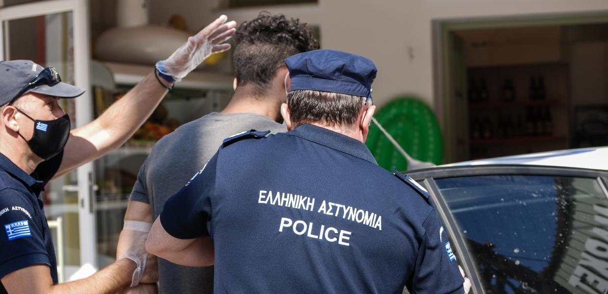 Αστυνομικοί βάζουν σε περιπολικό τον γυναικοκτόνο της Γαρυφαλλιάς