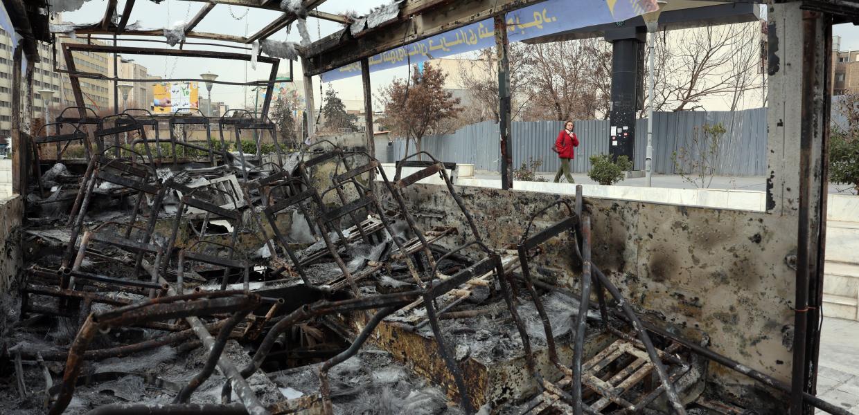 Κόσμος στι Ιράν περπατά δίπλα από λεωφορεία που κάηκαν στις μαζικές διαδηλώσεις