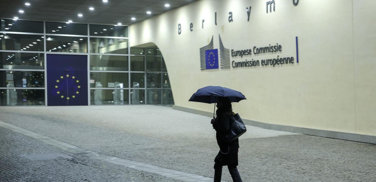Άνθρωπος με ομπρέλα περπατάει στην είσοδο κτιρίου της Κομισιόν στις Βρυξέλλες