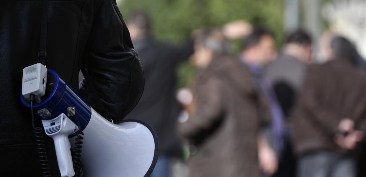 Άντρας κρατά ντουντούκα στον ώμο σε απεργιακή συγκέντρωση