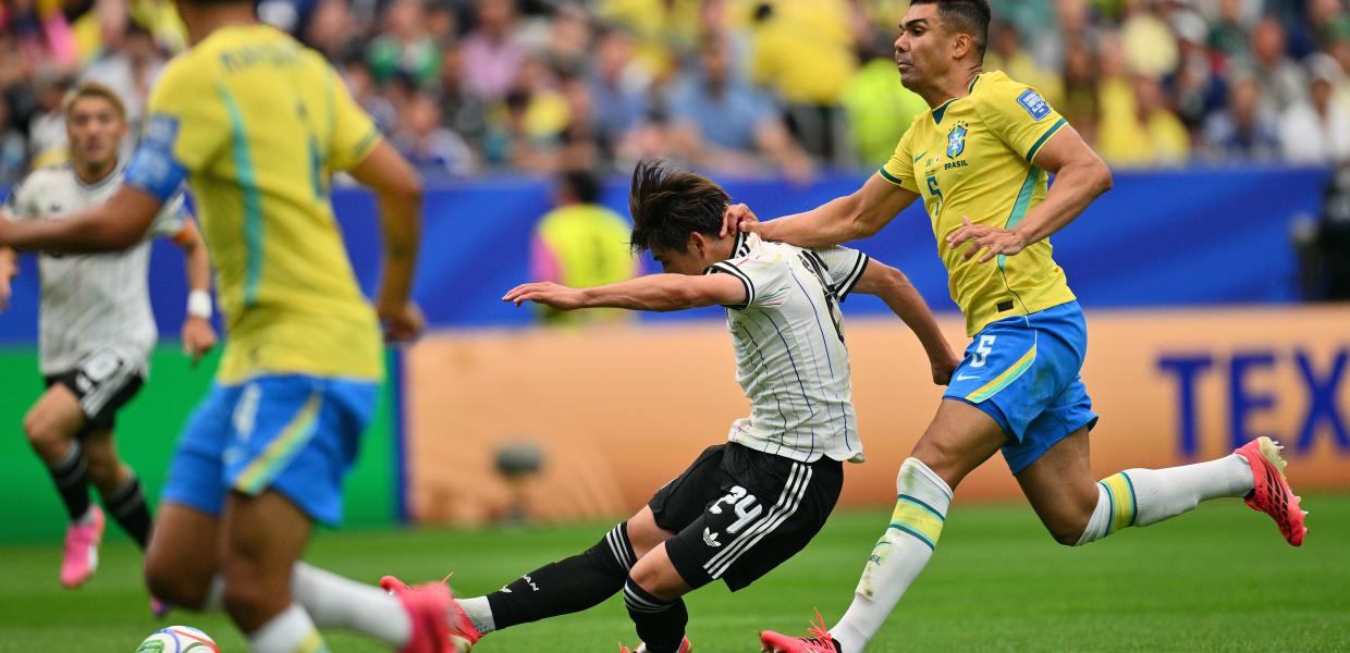 Kaishu Sano (C) of Japan scores the 1-0 lead under pressure from Casemiro (R) of Brazil during the FIFA World Cup 