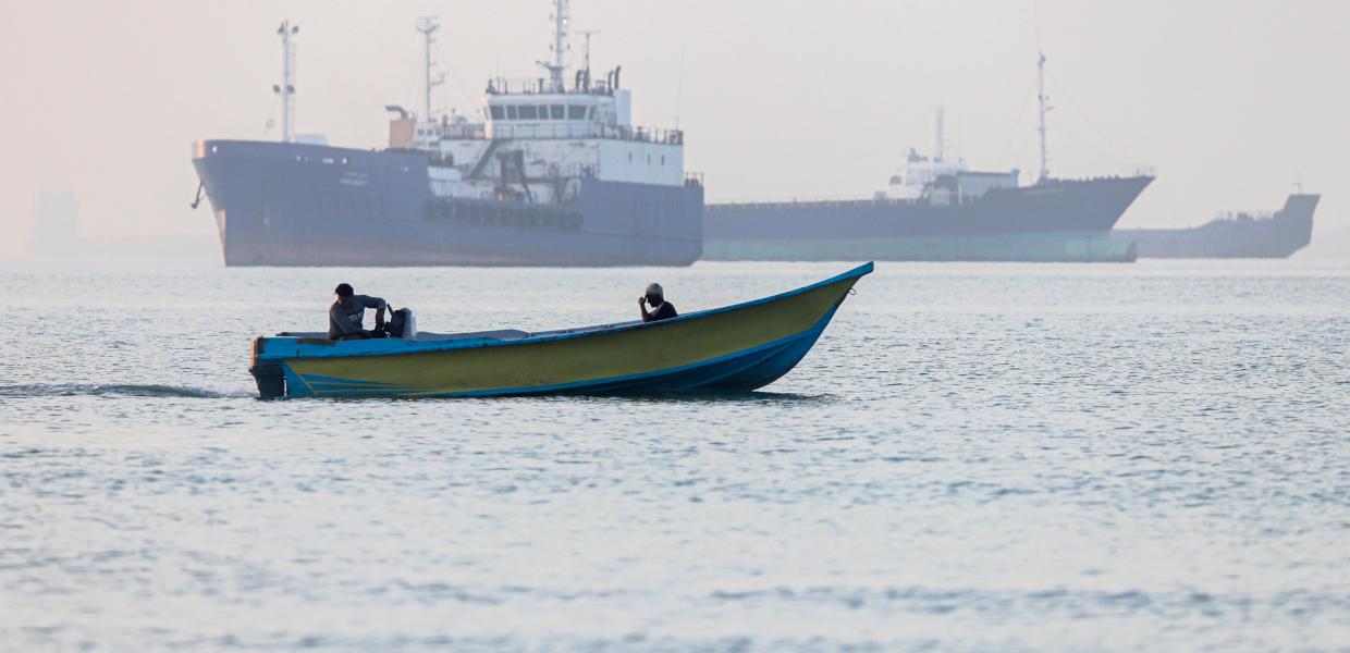 Ψαράδικιο περνά μπροστά από πλοίο που είναι κολλημένο στα Στενά του Ορμούζ