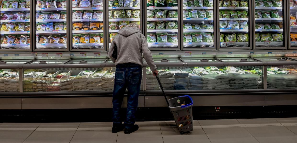 Άντρας κοιτάει προϊόντα μπροστά σε ψυγεία σούπερ μάρκετ με λαχανικά