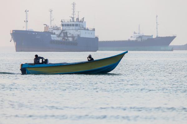 Ψαράδικιο περνά μπροστά από πλοίο που είναι κολλημένο στα Στενά του Ορμούζ